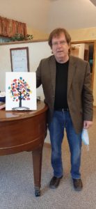 David Strom showing artwork done by Pioneer Cottages residents