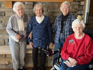 Dotty, Dorothy, Barbara, and Ardelle pose in front of fireplace at PioneerCare
